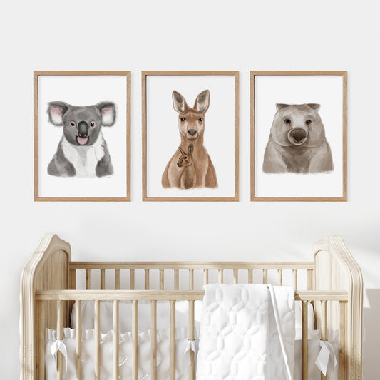 Three framed australian animal prints above a cot in a baby nursery