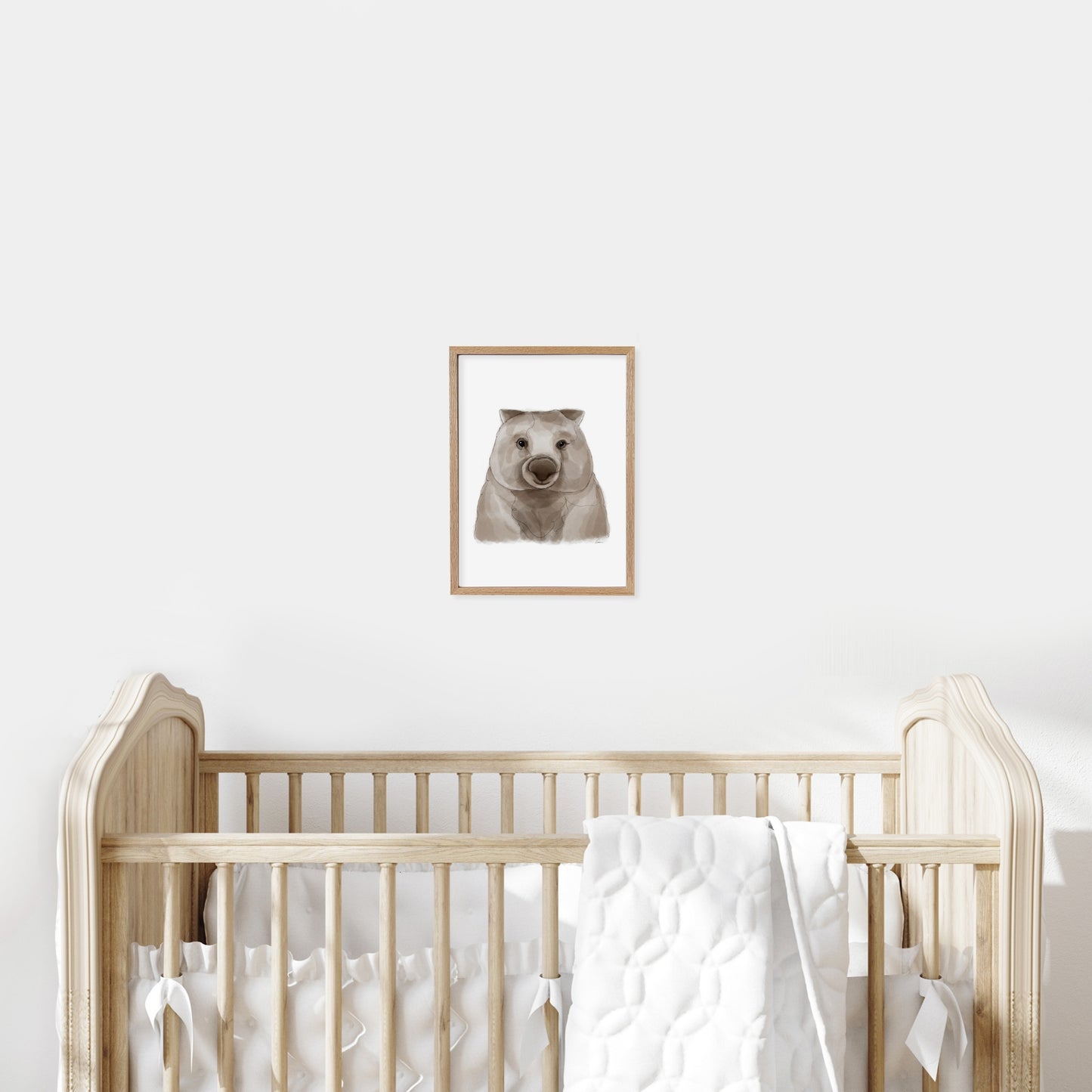Framed illustration of a wombat on a wall above a cot in a baby nursery.