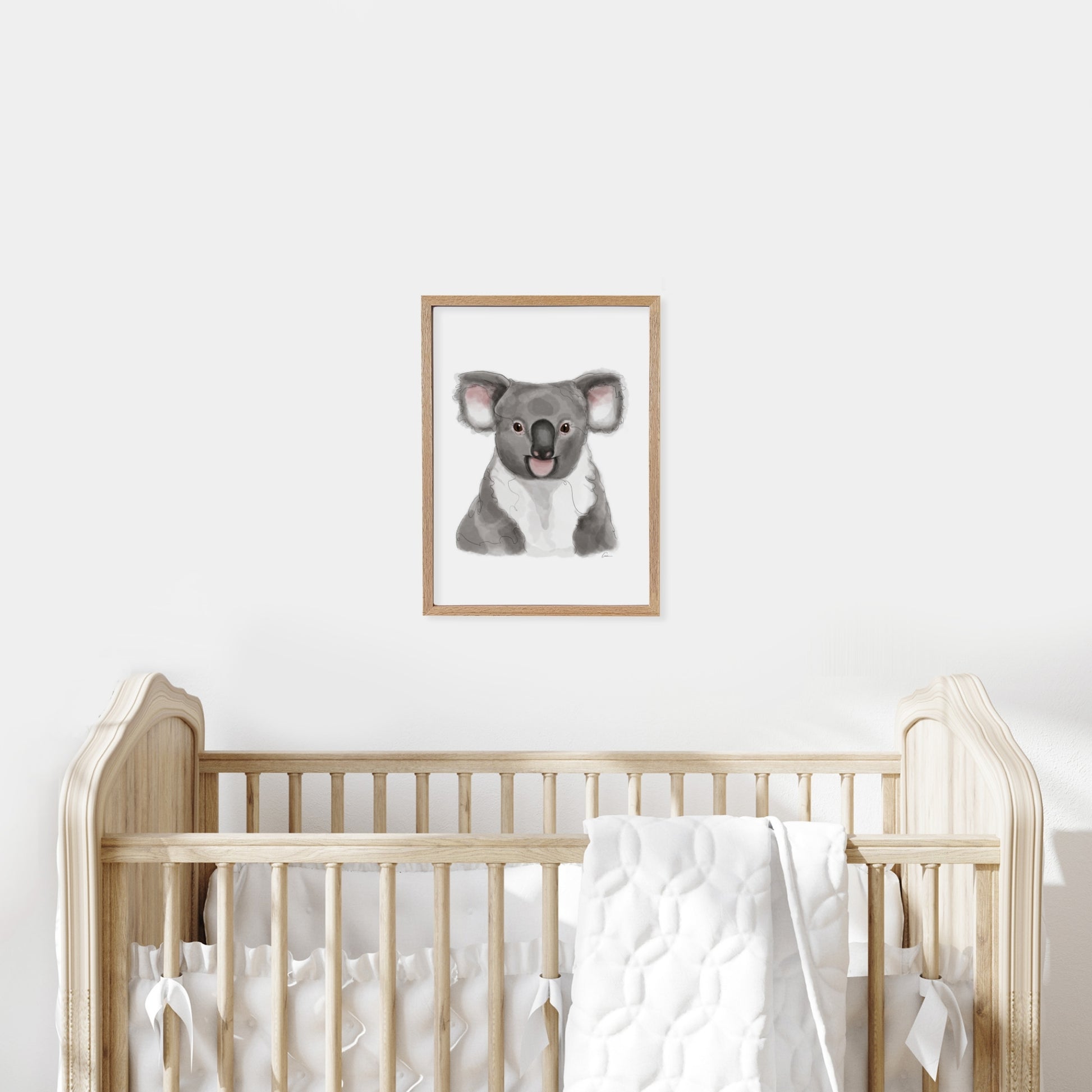 Framed illustration of a koala on a wall above a cot in a baby nursery.