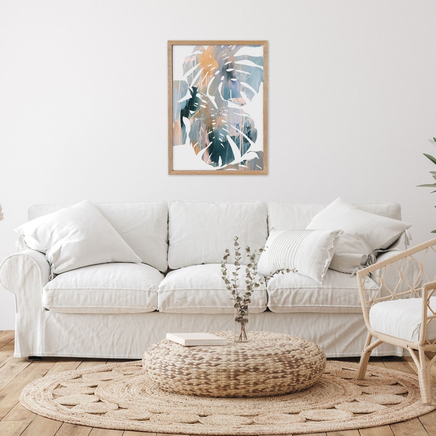 Abstract leaf wall art in living room with a white sofa, woven ottoman