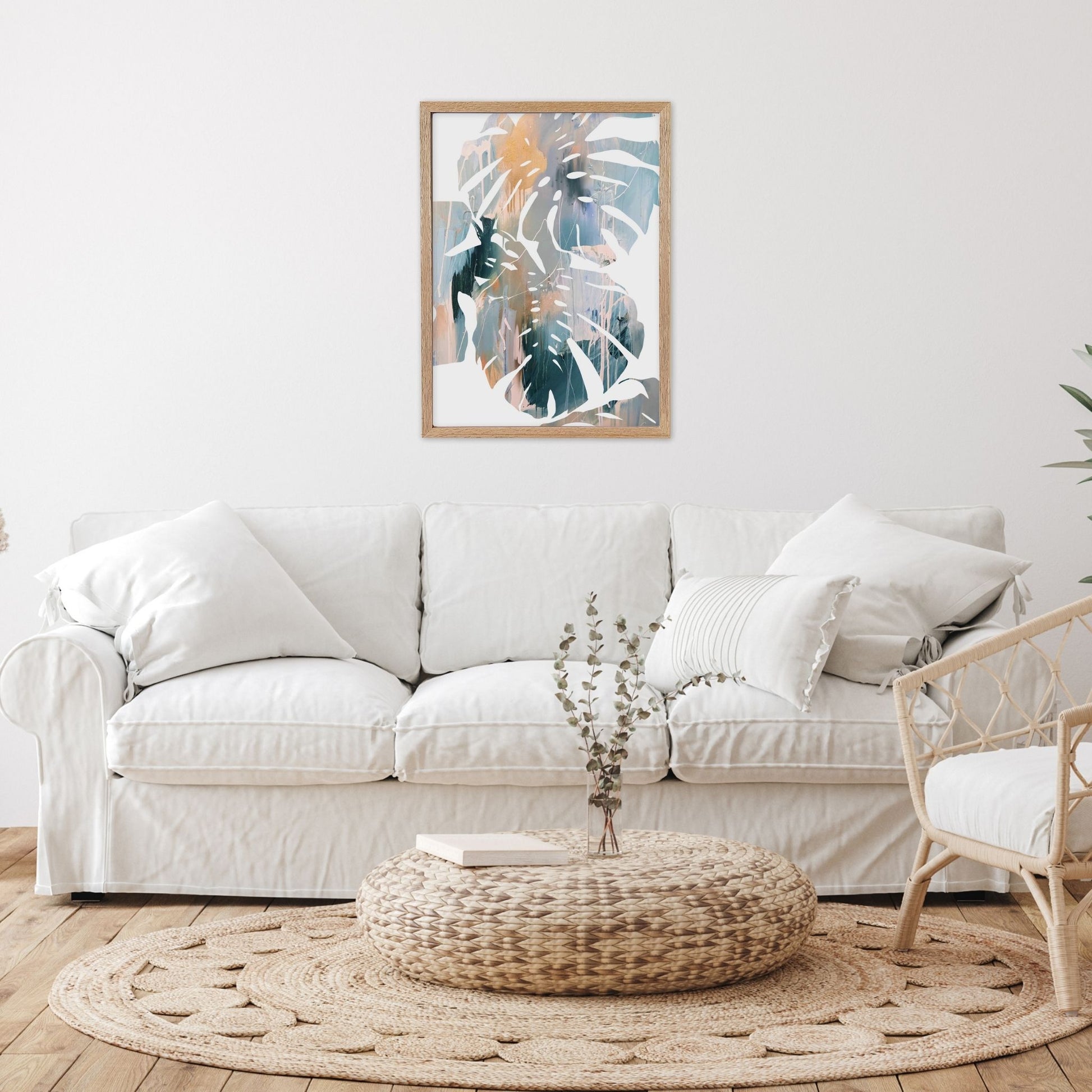 Abstract leaf wall art in living room with a white sofa, woven ottoman