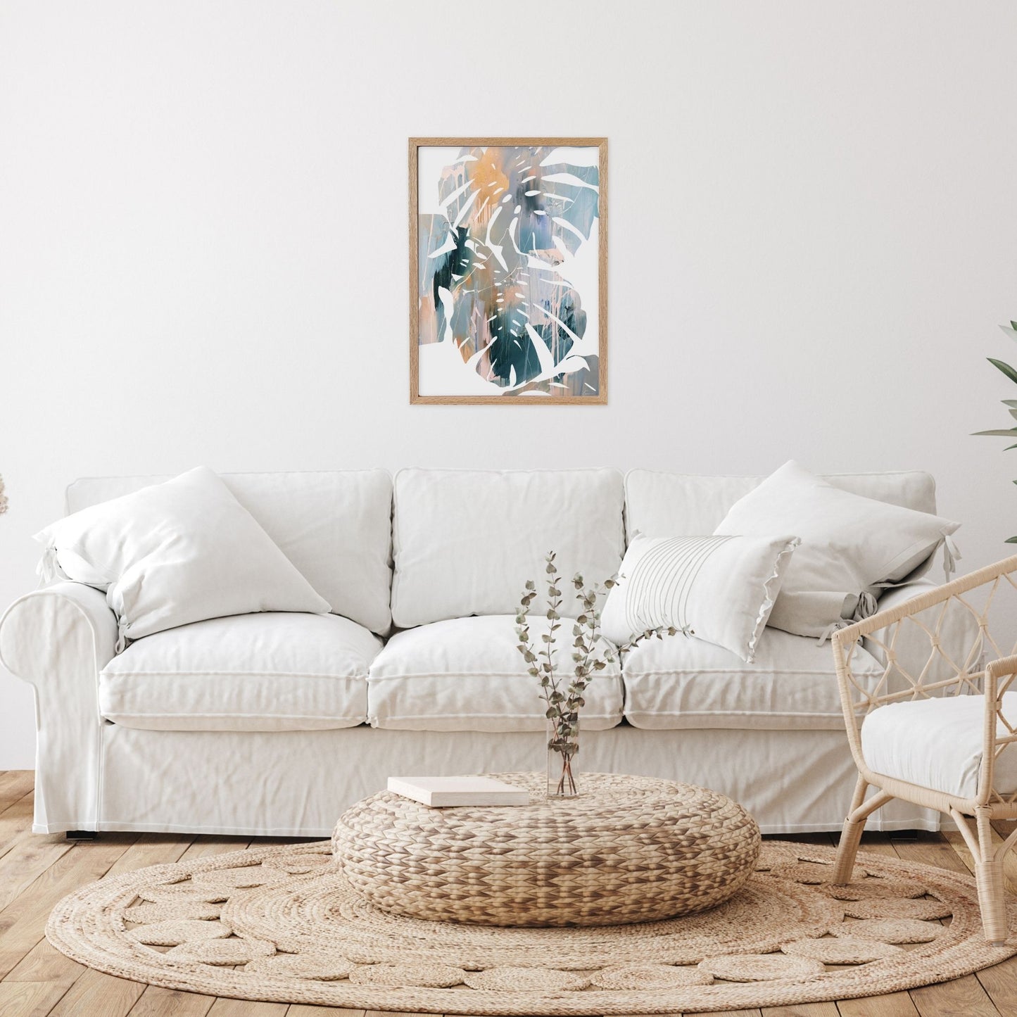 Abstract leaf wall art in living room with a white sofa, woven ottoman