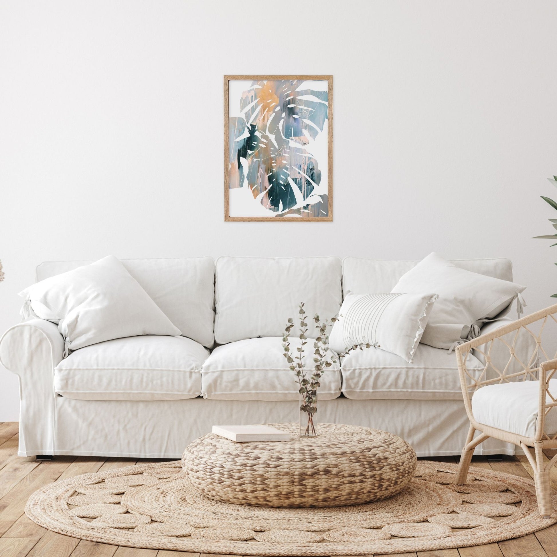 Abstract leaf wall art in living room with a white sofa, woven ottoman