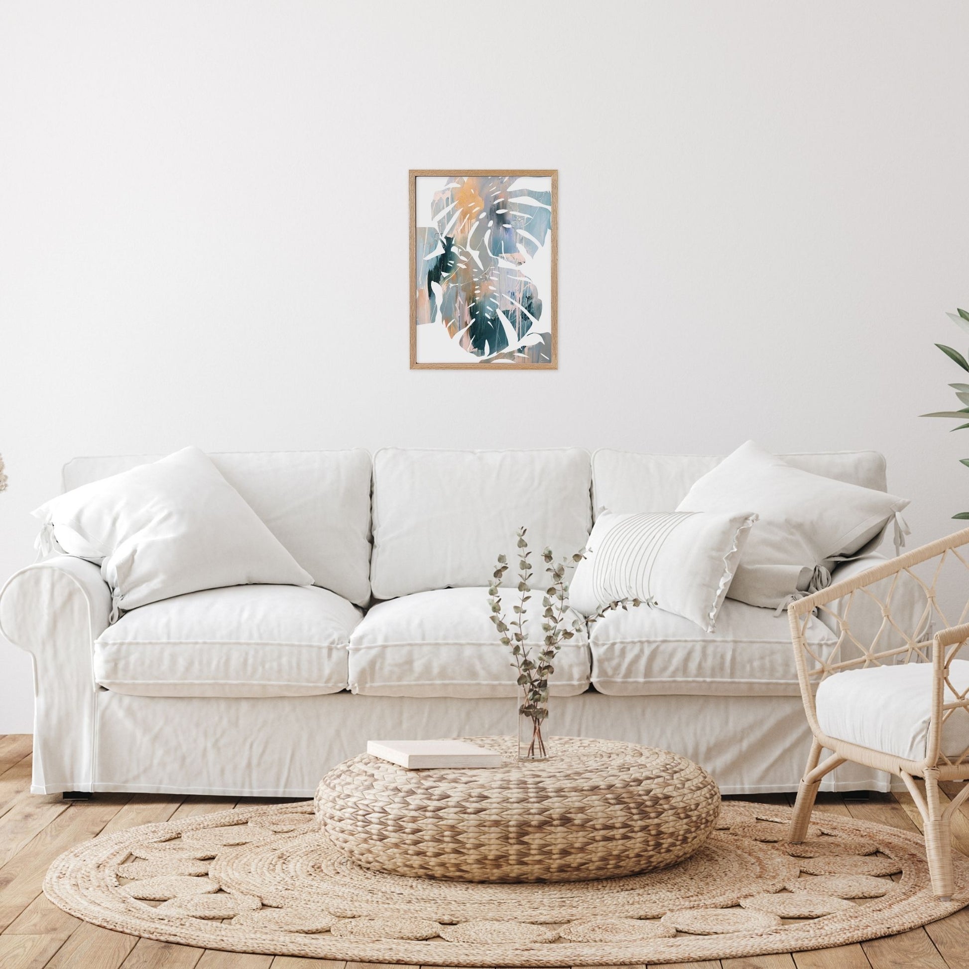 Abstract leaf wall art in living room with a white sofa, woven ottoman