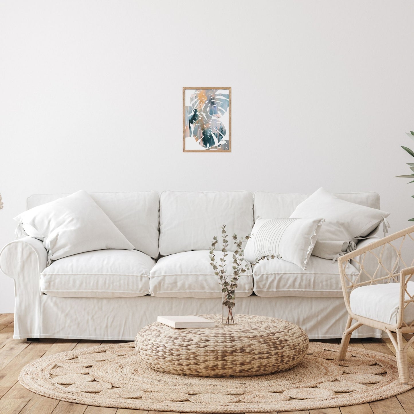 Abstract leaf wall art in living room with a white sofa, woven ottoman