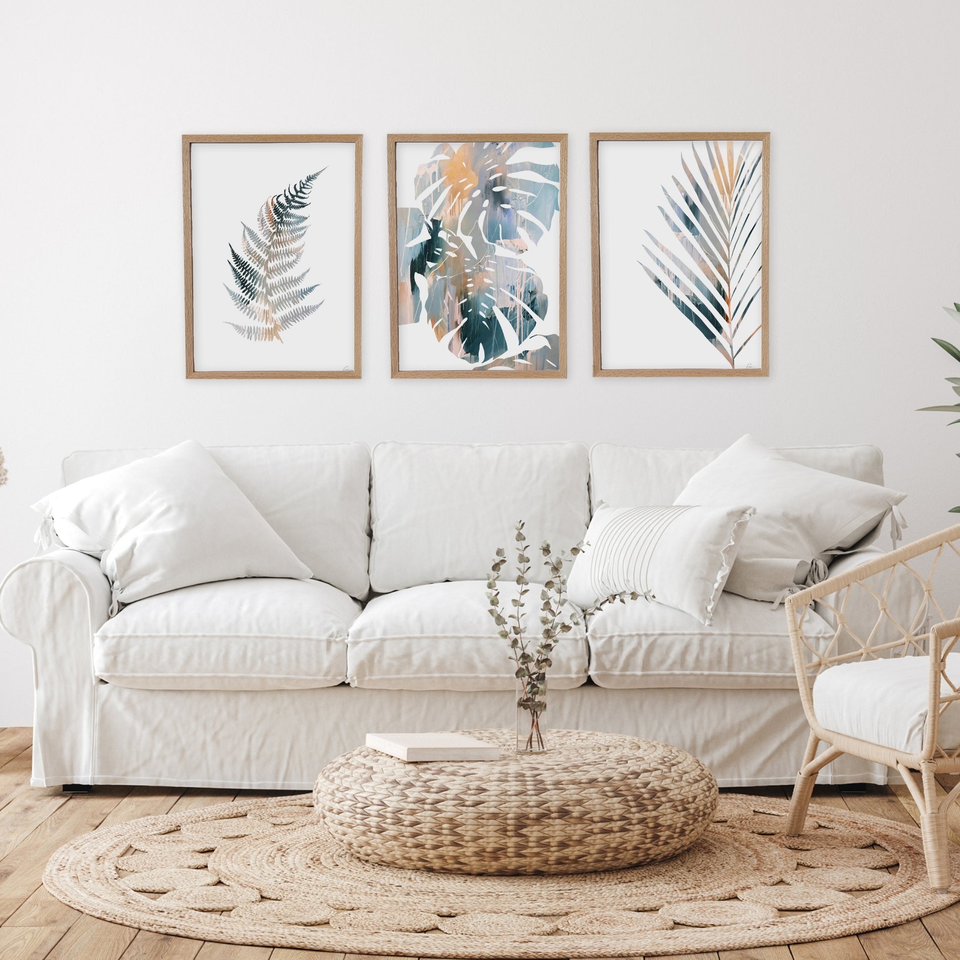 Living room with a white sofa, decorative pillows, and framed leaf art on the wall.
