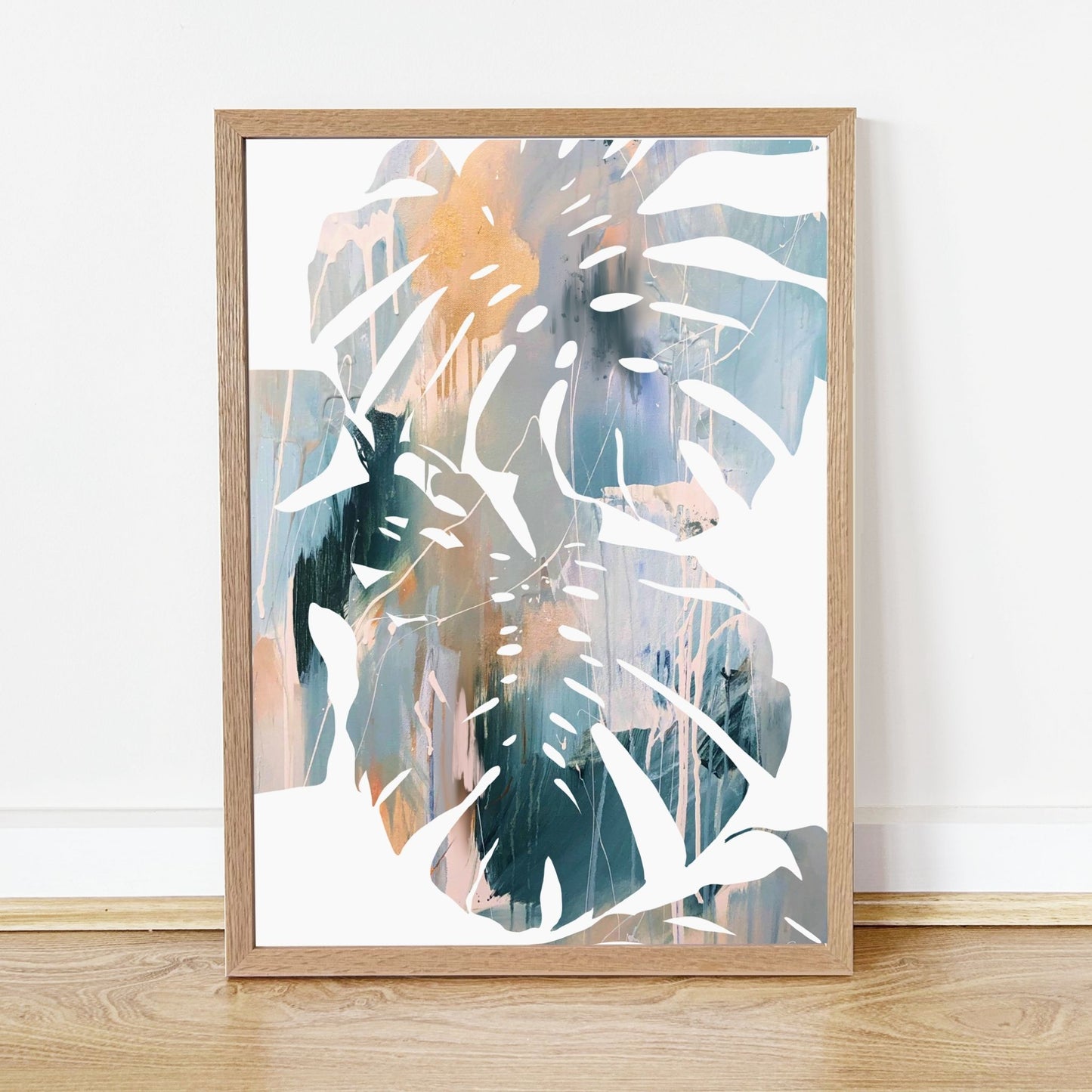 Framed abstract artwork with palm leaves on a white wall.