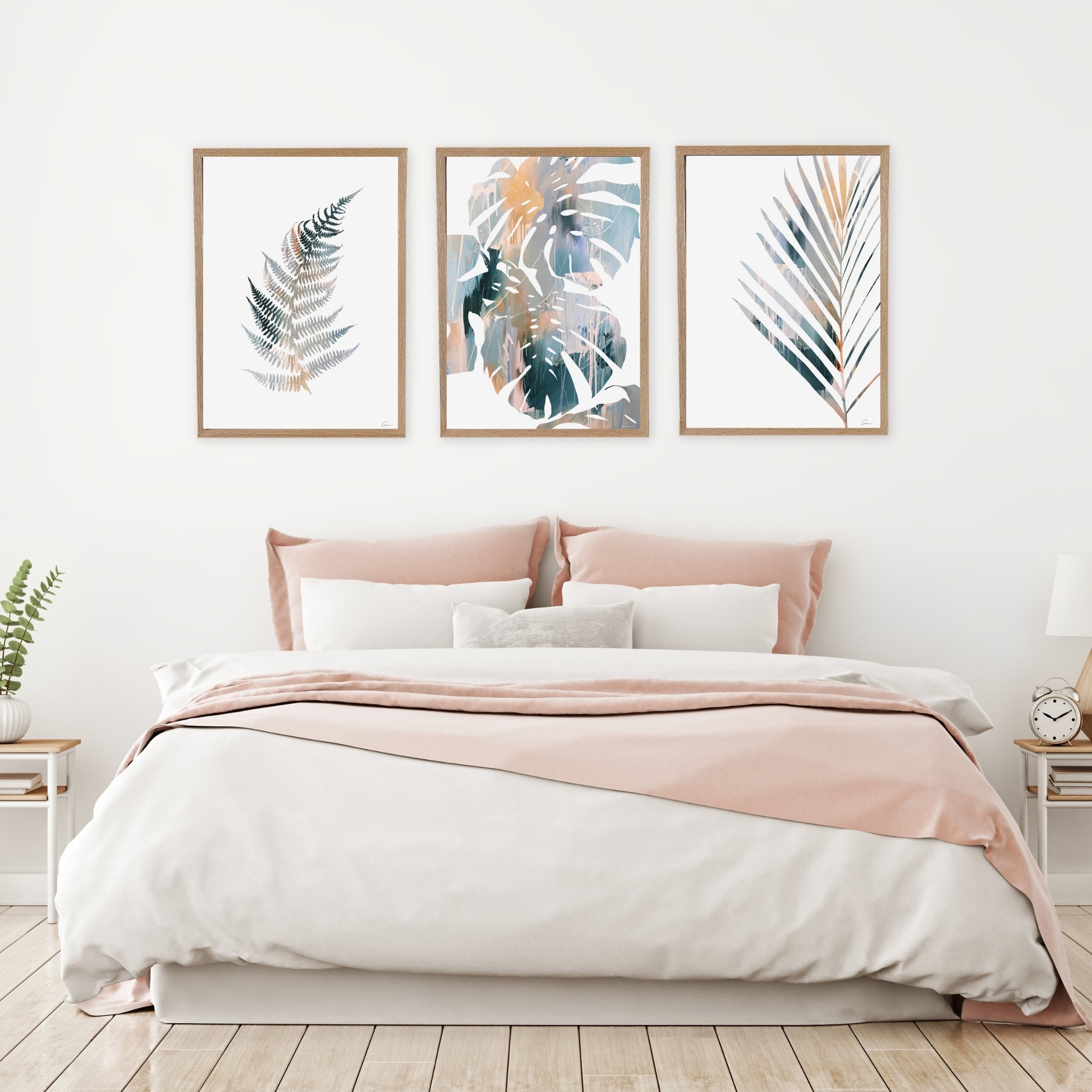 Bedroom with a bed featuring pink and white bedding, three framed leaf prints on the wall, and small side tables.