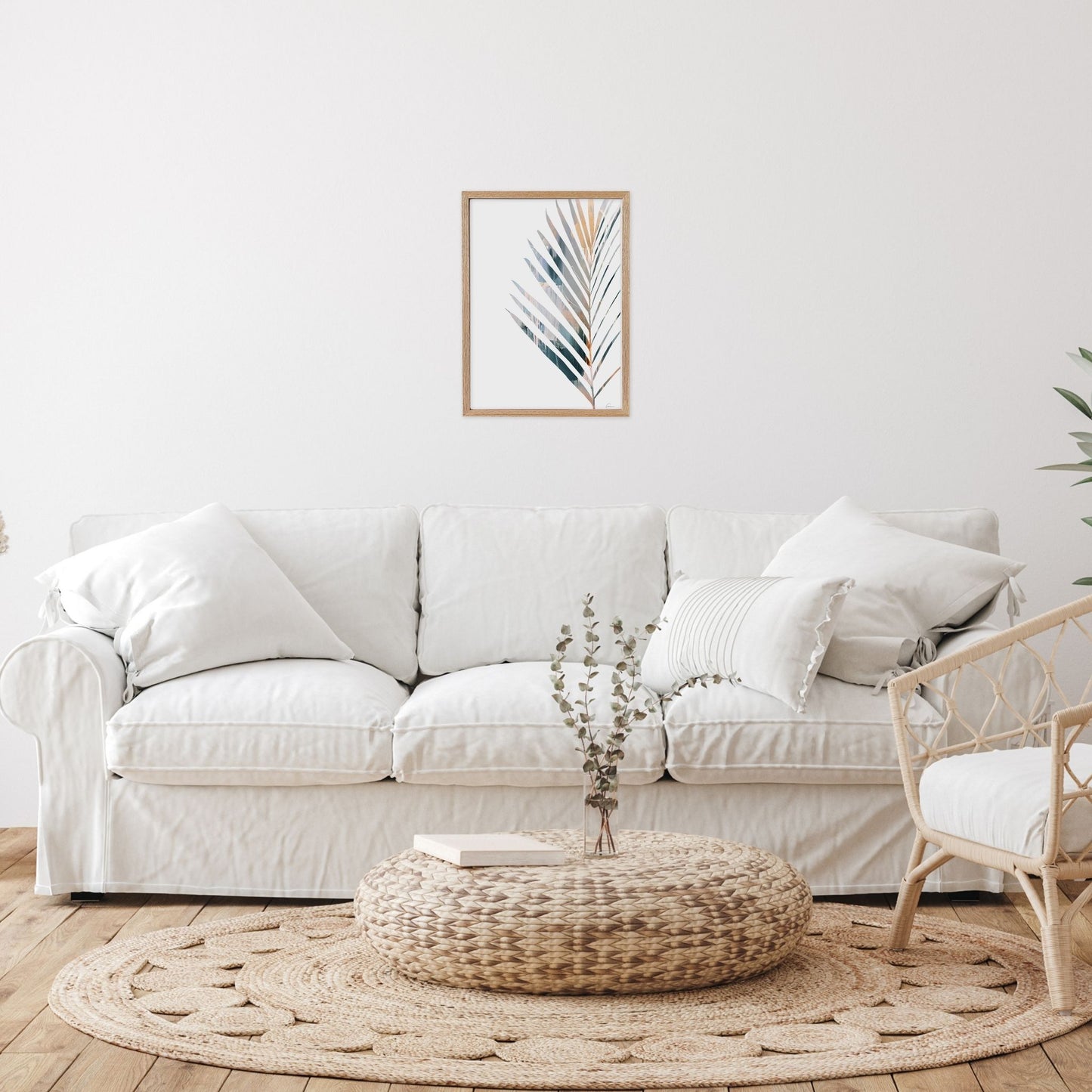 Framed artwork with Yucca leaf in Living room with a white sofa, woven ottoman, 