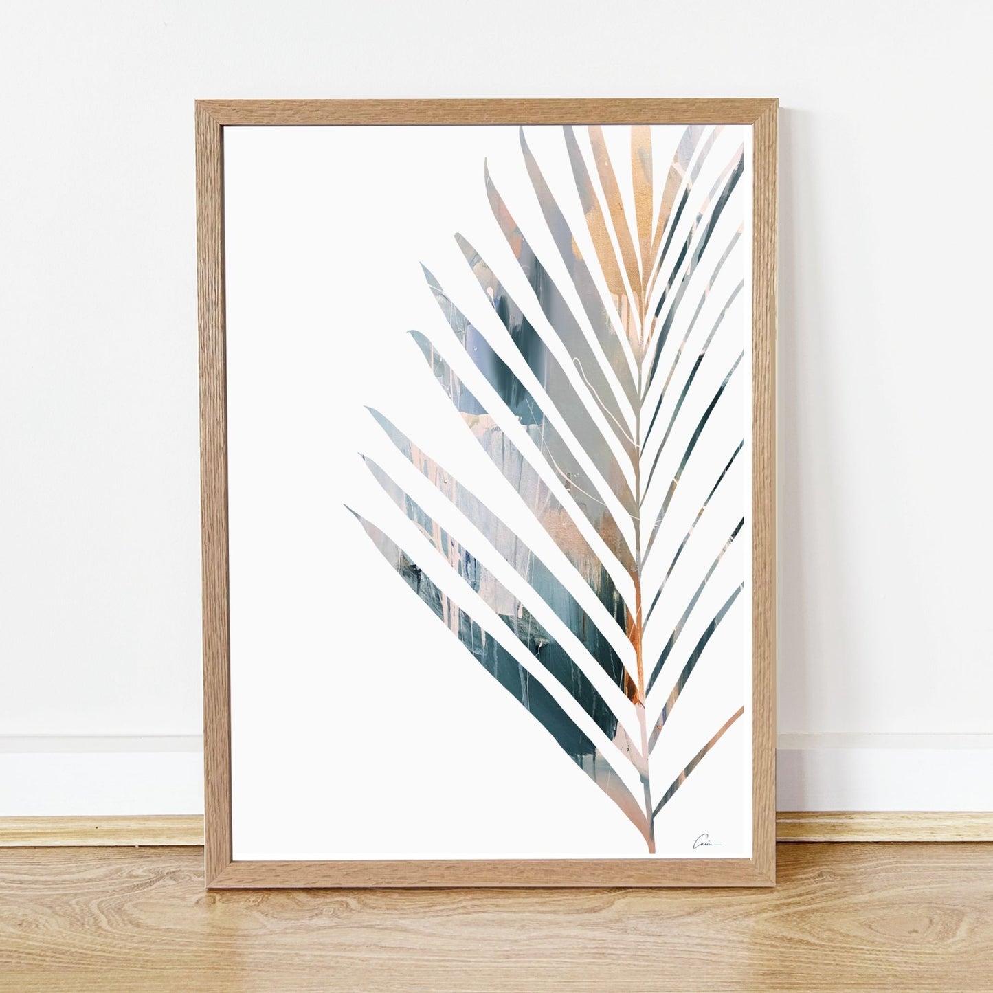 Framed artwork of a palm yucca leaf design on a white wall.